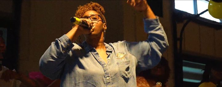A worship leader singing with her arm raised at Pentecost 2025