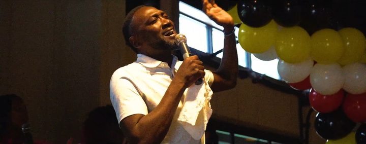 A speaker mid-sermon in front of the balloon arch