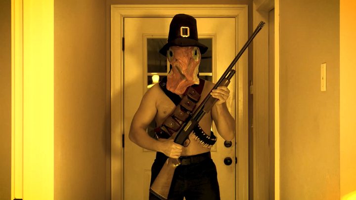 A masked pilgrim with a shotgun in a doorway