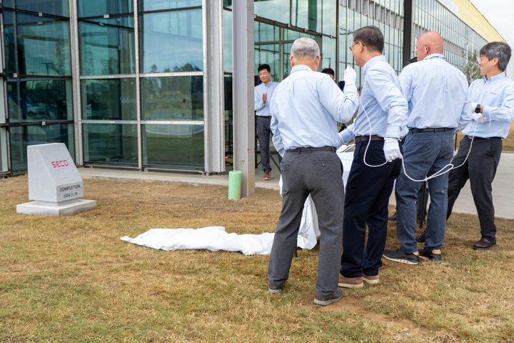 Executives pulling the cover off the completion stone
