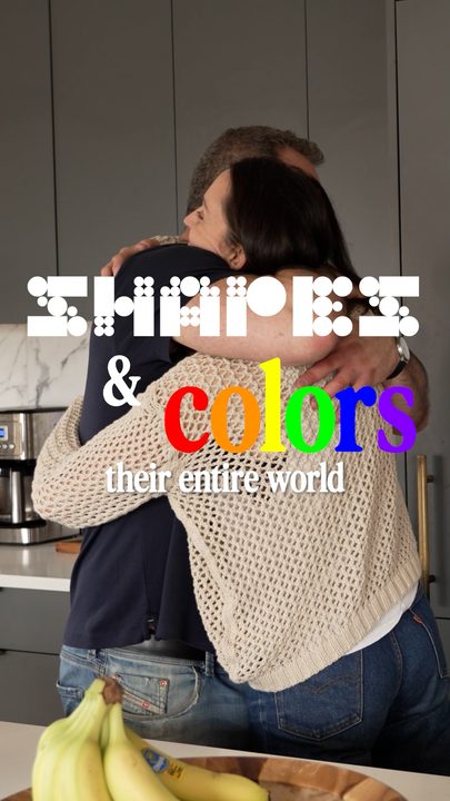 A couple embracing in a kitchen under playful 'shapes and colors' type